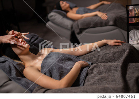 two attractive women are pampered themselves at the health spa, get face lift massage 64807461