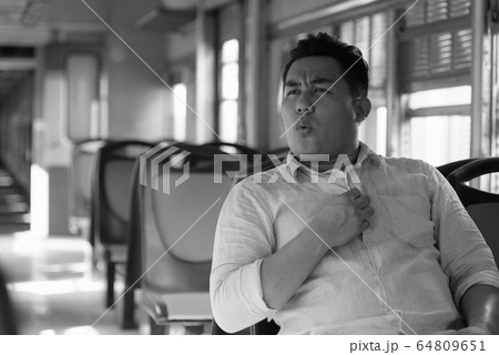 Stressed overweight Asian tourist man feeling hot inside the train Stressed overweight Asian tourist man feeling hot inside the train 64809651