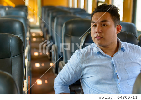 Young overweight Asian tourist man riding inside the train Young overweight Asian tourist man riding inside the train 64809711