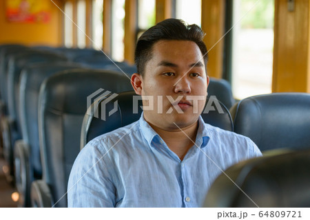Young overweight Asian tourist man riding inside the train 64809721