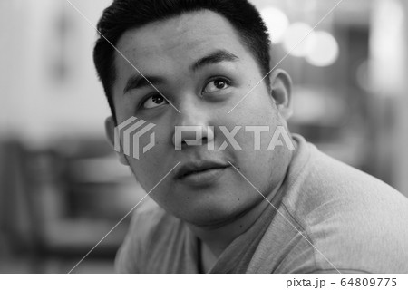 Face of young overweight Asian man thinking at the coffee shop 64809775