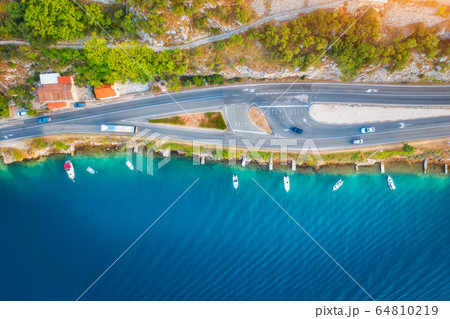 Aerial view of road in beautiful green forest and boats in the sea at sunset in summer. landscape 64810219