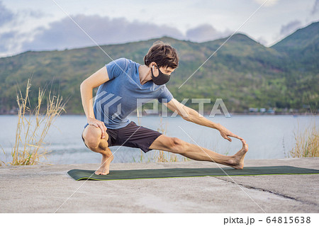 Young man in medical mask performing some workouts in the park during coronavirus quarantine 64815638
