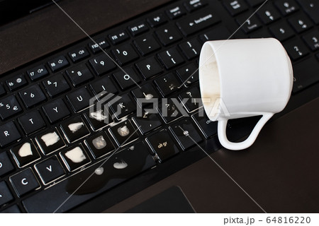 Spill coffee from white cup on the computer laptop 64816220