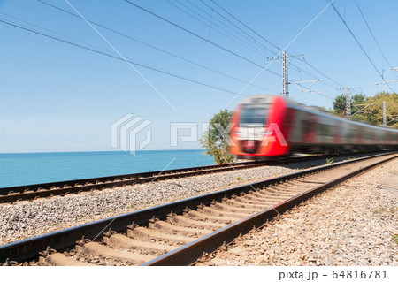 passenger train goes along the seashore in day 64816781