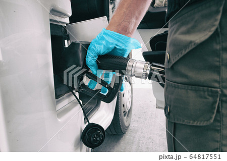Coronavirus gas oil prices dropping man pumping gasoline at gas station wearing medical blue glove as COVID-19 spreading safety protection for touching germs 64817551
