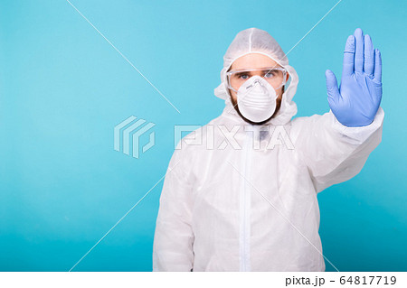 Doctor or lab scientist wearing biohazard protective suit hand gesturing Stop Coronavirus COVID-19 disease global pandemic outbreak. Restrictive no entry, quarantine order. Copy space. Doctor or lab scientist wearing biohazard protective suit hand gesturing Stop Coronavirus COVID-19 disease global pandemic outbreak. Restrictive no entry, quarantine order. Copy space. 64817719