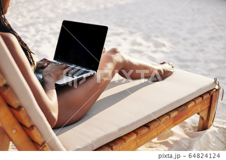Woman working on laptop on beach 64824124
