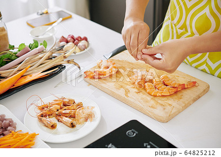 Housewife peeling boiled shrimps 64825212