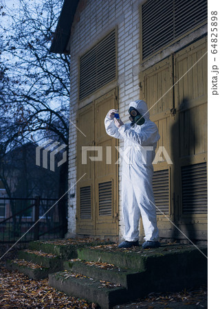 Scientist doing research outdoors, wearing white coverall and gas mask Scientist doing research outdoors, wearing white coverall and gas mask 64825898