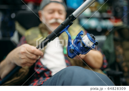 Angler with rod sitting in chair, fishing shop Angler with rod sitting in chair, fishing shop 64828309