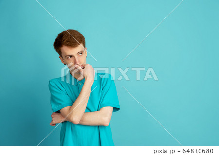 Caucasian young man's monochrome portrait on blue studio background, emotinal and beautiful 64830680
