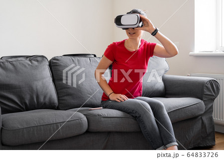 Woman sitting at home on the sofa with vr glasses. Online shopping, watching movie, video call 64833726