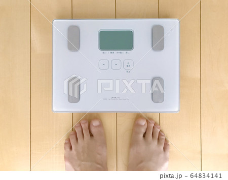 体重計に乗ろうとする人の写真素材