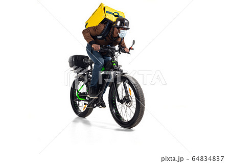Too much orders. Contacless delivery service during quarantine. Man delivers food and shopping bags during isolation, wearing helmet and face mask. 64834837