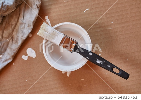 Paint brush on a can of white wall paint 64835763