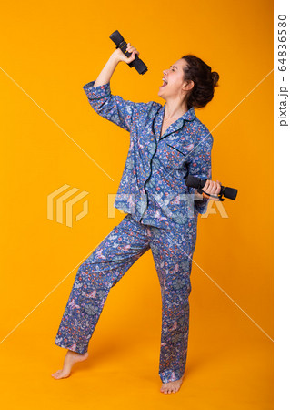 Smiling young girl in pajamas home wear posing while resting at home isolated on yellow background studio portrait. Relax good mood lifestyle concept. 64836580