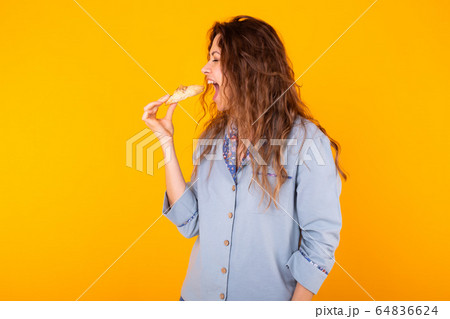 Joyful woman wears fashion pajama going to eat small delicious croissant on yellow background. Morning, breakfast and home wear concept. 64836624