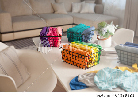 Spring cleaning of closet. Vertical tidying up storage. Neatly folded bright color clothes in the metal black baskets for wardrobe. Spring cleaning of closet. Vertical tidying up storage. Neatly folded bright color clothes in the metal black baskets for wardrobe. 64839331