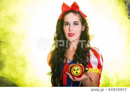Woman dressed as fairytale character holds Radioactive atomic nuclear ionizing radiation danger warning symbol on apple. Nuclear and radiation measurement concept. 64839947