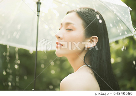 きれい 女性 雨 降る 傘 濡れる 人物 素材の写真素材