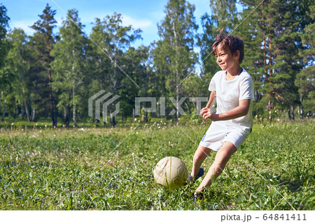 kid kicking a soccer ball on the field kid kicking a soccer ball on the field 64841411