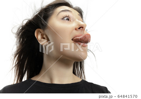 Smiling girl opening her mouth and showing the long big giant tongue isolated on white background, crazy and attracted 64841570