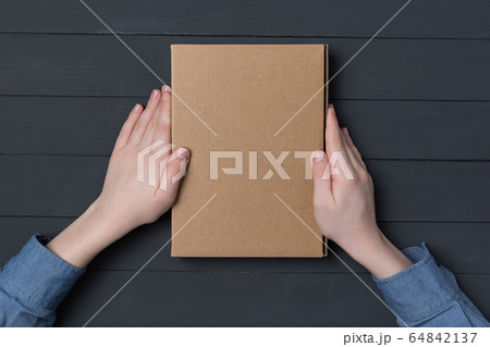 Cardboard box in children's hands on black 64842137