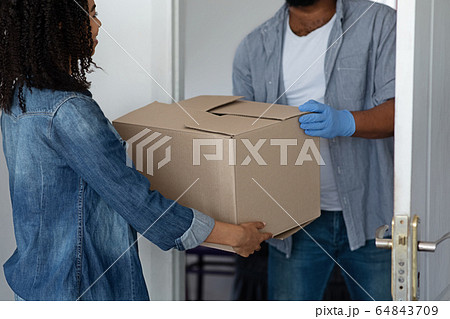 Unrecognizable Black Delivery Man Delivering Package To Woman Homeowner Unrecognizable Black Delivery Man Delivering Package To Woman Homeowner 64843709