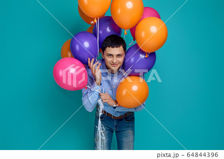 man in shirt holding bright colorful balloons man in shirt holding bright colorful balloons 64844396
