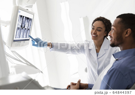 Friendly dentist showing patient his teeth on xray 64844397