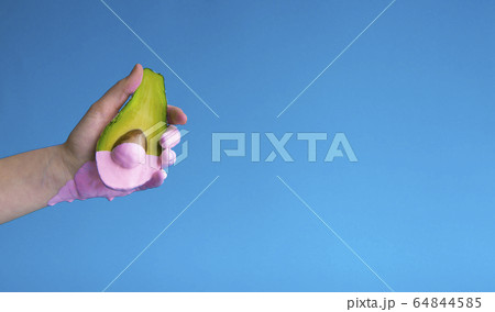 Pink paint dripping from half avocado in hand Pink paint dripping from half avocado in hand 64844585