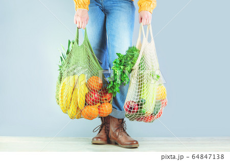 Unrecognizable girl holds two mesh shoppers with 64847138