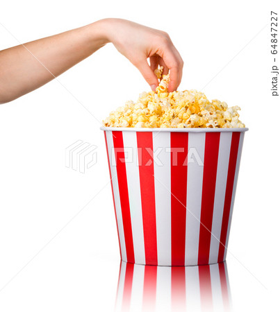 Woman hand picking popcorn from striped bucket Woman hand picking popcorn from striped bucket 64847227