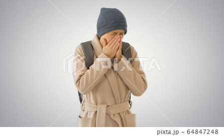 Woman in a coat walking and coughing on gradient background. Woman in a coat walking and coughing on gradient background. 64847248