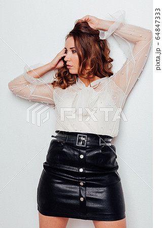 portrait of a beautiful woman with curls in a blouse and a black skirt 64847333