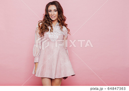Portrait of a beautiful fashionable woman with curls in a pink dress 64847363