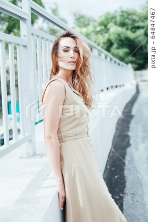 Portrait of a beautiful fashionable blonde woman in a beige dress Portrait of a beautiful fashionable blonde woman in a beige dress 64847467