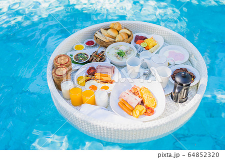 Floating breakfast set in tray with fried egg omelette sausage ham bread fruit milk juice coffee 64852320