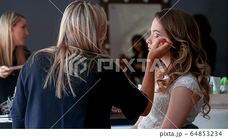 Makeup artist paints the eyes of a girl model Makeup artist paints the eyes of a girl model 64853234