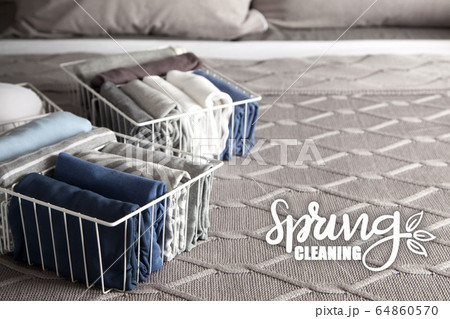 Spring cleaning of closet. Vertical tidying up storage. Neatly folded clothes in the metal white baskets for wardrobe. Grey background. 64860570