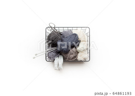 Yarn of gray, white and dark shades in a black metal basket. Knitting needles. Nordic style. Minimalism. Yarn of gray, white and dark shades in a black metal basket. Knitting needles. Nordic style. Minimalism. 64861193