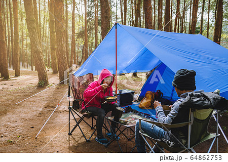 young asian couple of happy enjoying Camping in the pine forest Sit and eat food at the Camping young asian couple of happy enjoying Camping in the pine forest Sit and eat food at the Camping 64862753