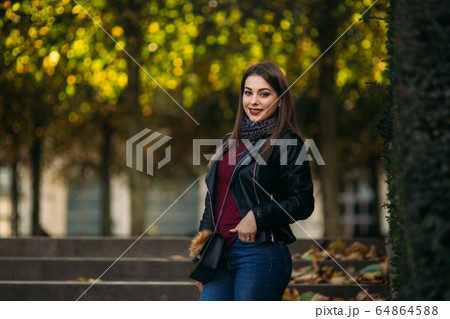 Stylish beautiful lady in a black leather jacket with a black bag and burgundy blouse Stylish beautiful lady in a black leather jacket with a black bag and burgundy blouse 64864588