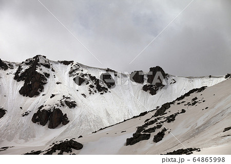 Rocks with snow cornice and traces from avalanche Rocks with snow cornice and traces from avalanche 64865998