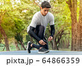 young man runner tying shoelace in park ready for running in morning . sport outdoors healthy 64866359