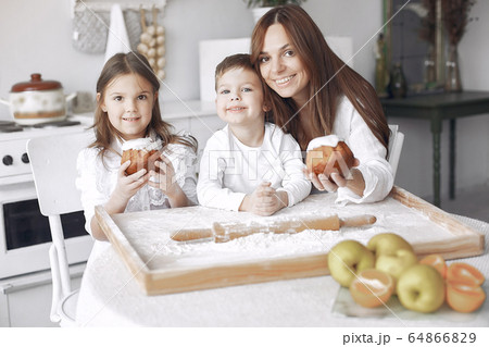 Family sitting in a kitchen and cook the dough for cake Family sitting in a kitchen and cook the dough for cake 64866829