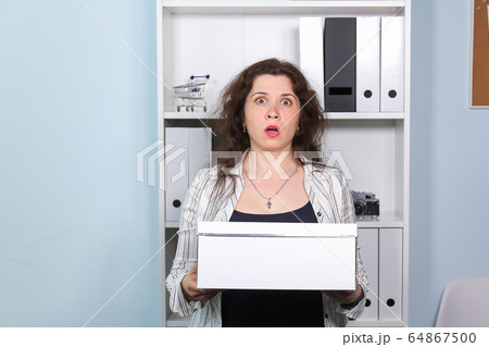 Concept of dismissal from work. Stunned woman with carton box with her stationery stuff, girl was fired from her job. Concept of dismissal from work. Stunned woman with carton box with her stationery stuff, girl was fired from her job. 64867500