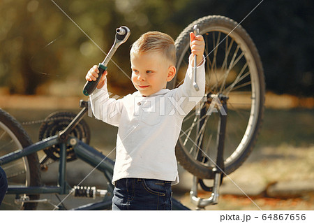 Little boy repair his bike in a park Little boy repair his bike in a park 64867656