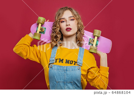 Nice woman with skateboard on red background 64868104